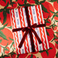 Gift wrapped in red and white striped paper with blue fishes with a brown ribbon on a festive background.