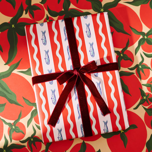 Gift wrapped in red and white striped paper with blue fishes with a brown ribbon on a festive background.