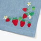 Blue apron with red straps. This apron is dedicated to strawberries with embroidery of strawberries in a basket and on a vine with little white flowers.