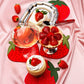 Dessert platter with strawberry-themed decor on a pink fabric background. Showcasing strawberry napkins