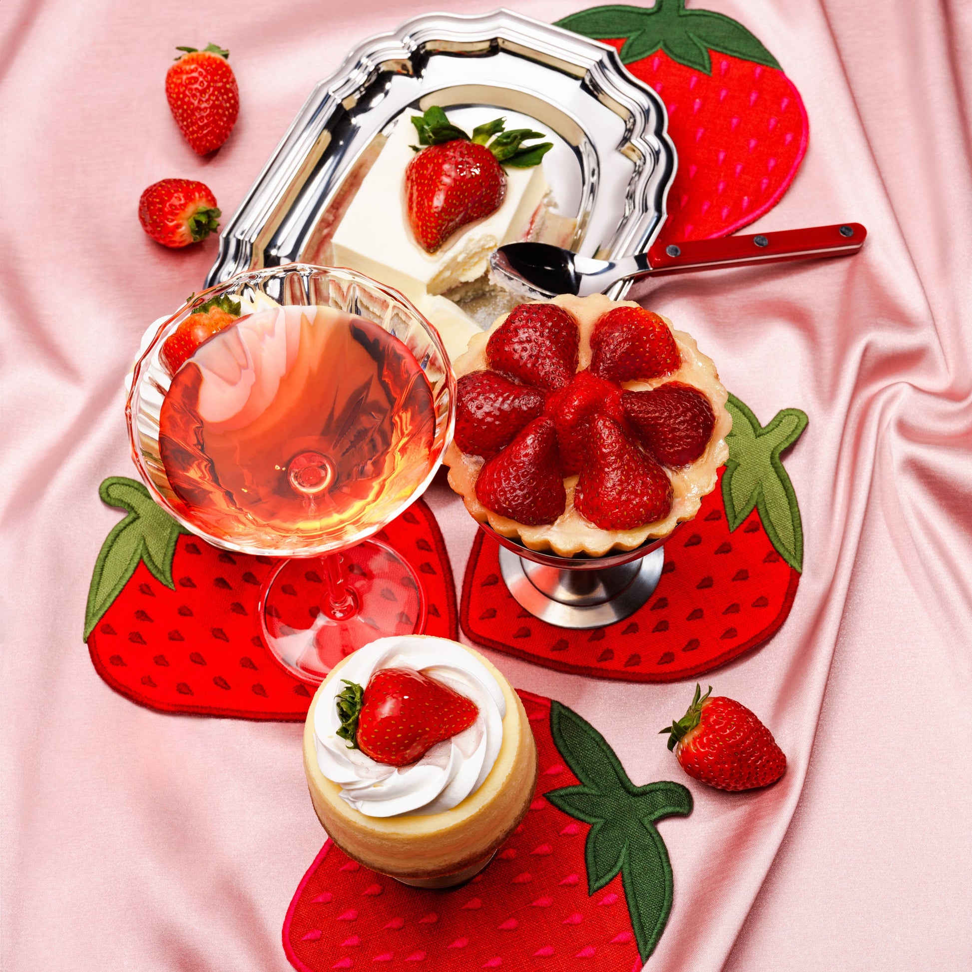 Dessert platter with strawberry-themed decor on a pink fabric background. Showcasing strawberry napkins
