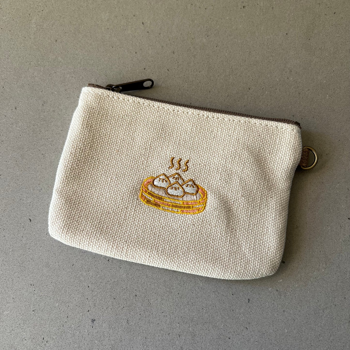 Pouch that has a steamer basket with 4 steaming bao embroidered on the front