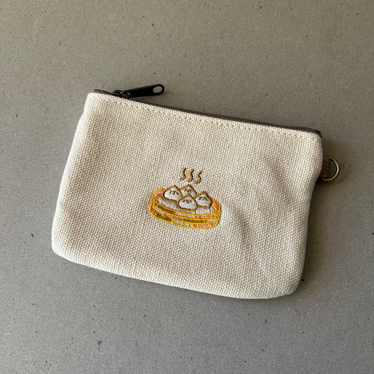 Pouch that has a steamer basket with 4 steaming bao embroidered on the front