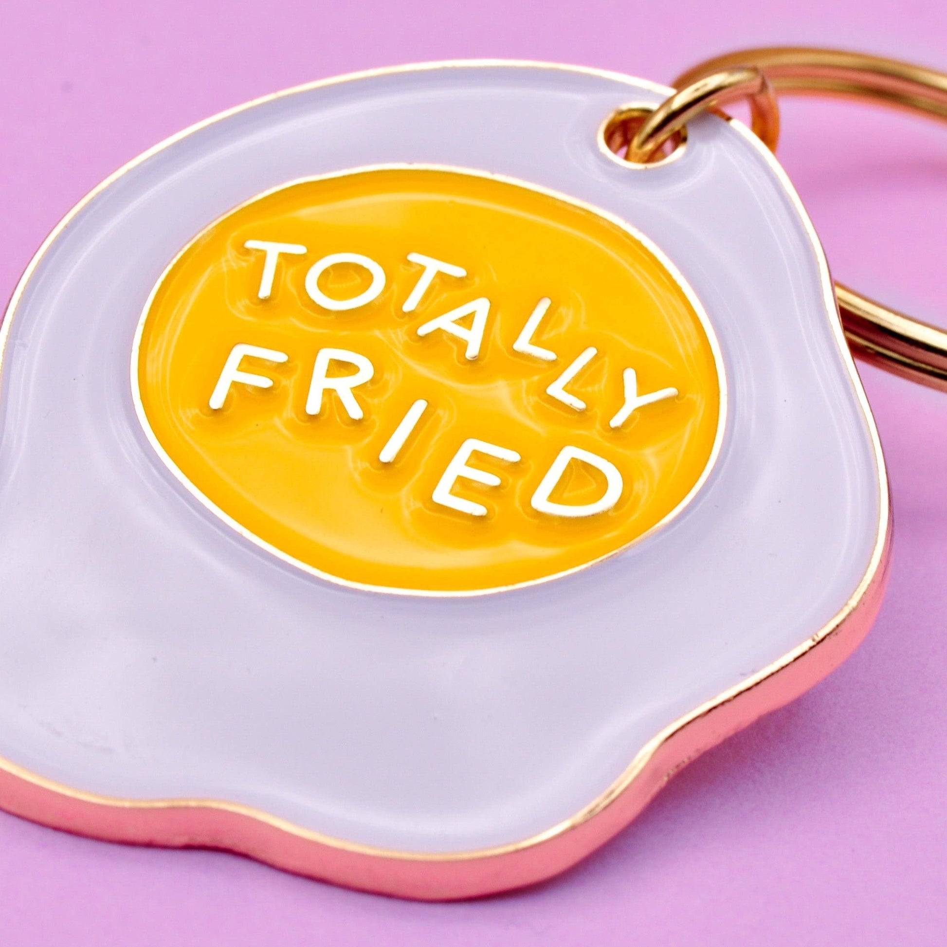 Enamel keychain of an egg that says Totally Fried.