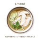 Picture of an udon dish that has citrus slices, herbs and king mushrooms with noodles and broth.