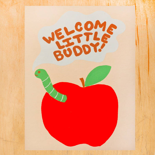 Card with a red apple and green worm on a beige background, featuring the text 'Welcome Little Buddy'.
