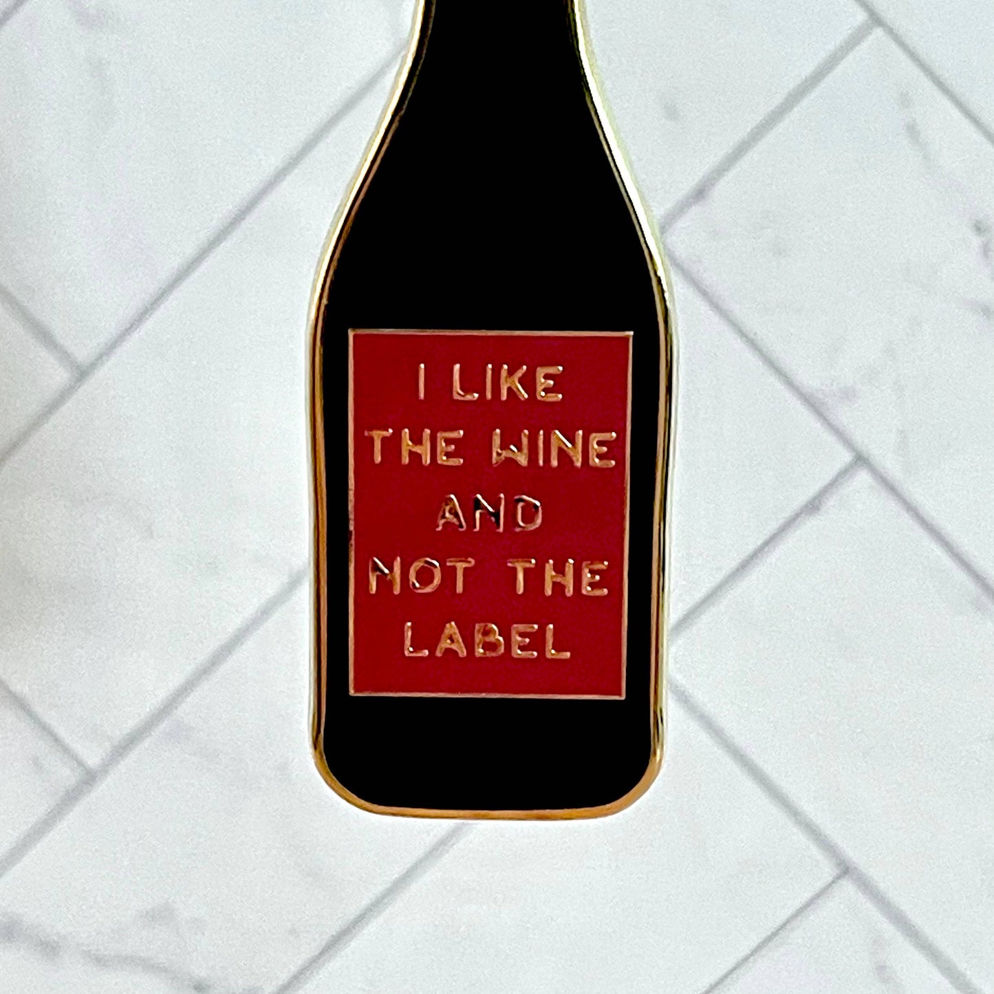 Close up of keychain to show enamel detailing. Text reads: I like the wine and not the label.