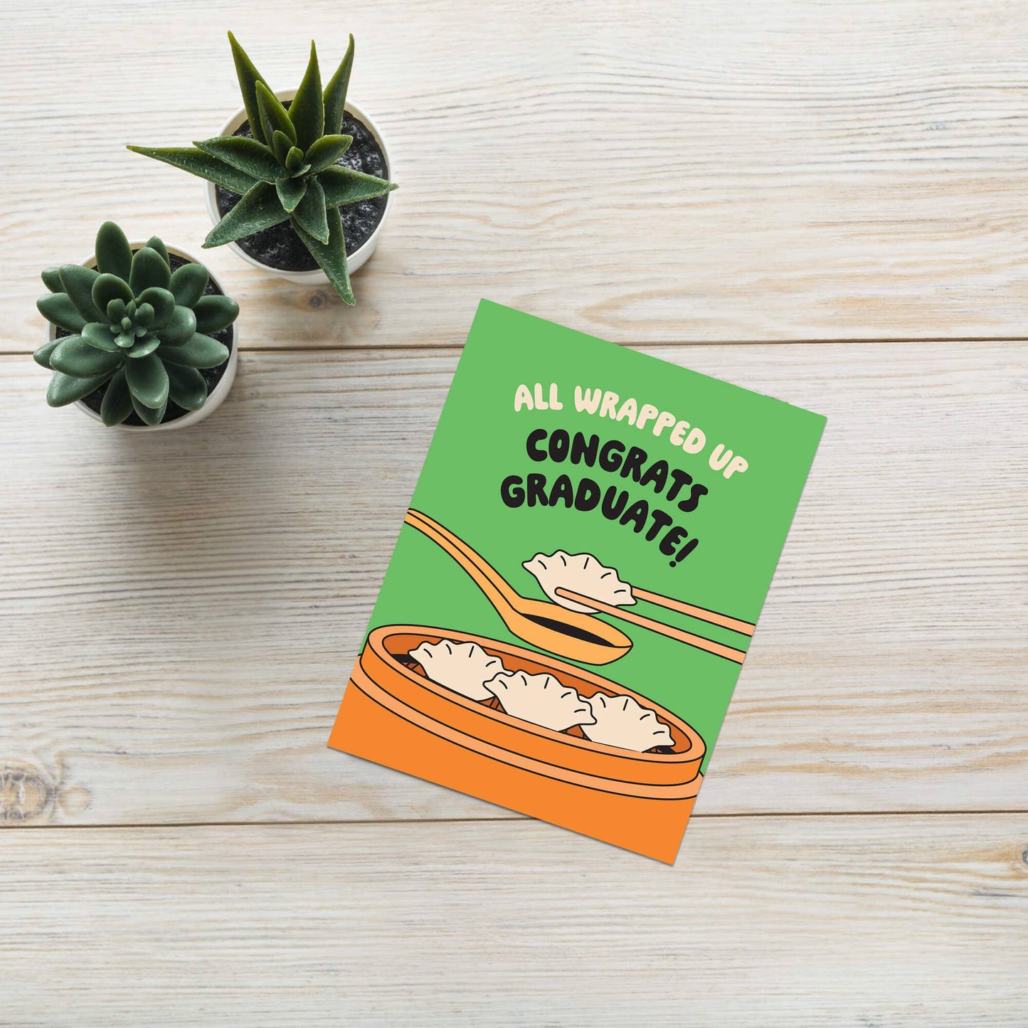 Graduation card with cartoon design on a wooden surface with plants