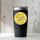 Black tumbler with a yellow sticker featuring a wedge of cheese and text on a wooden surface.