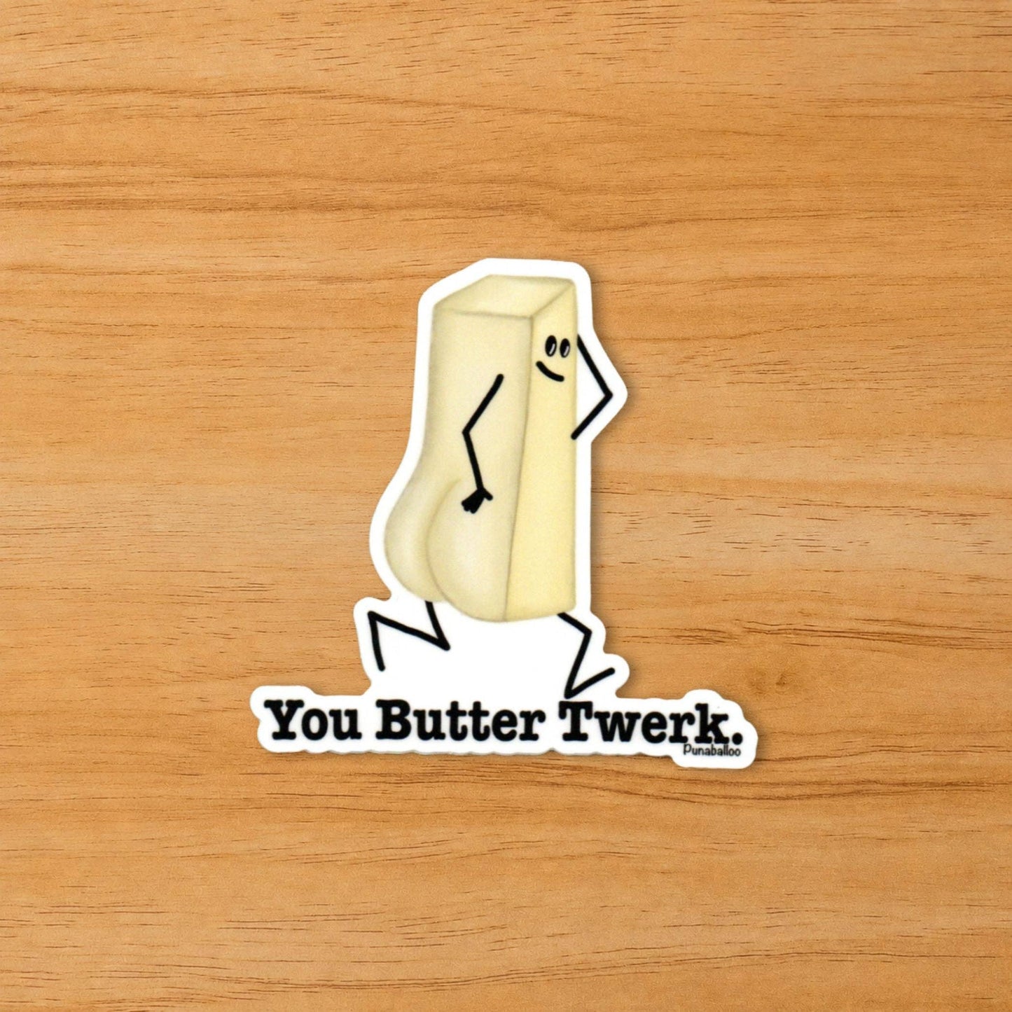 A die-cut sticker featuring a cartoon stick-figure-style butter block with the text 'You Butter Twerk.' on a light wood background.