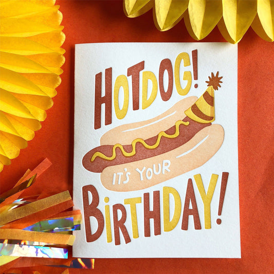 Greeting card with a yellow envelope -- text reads "Hotdog! it's your birthday!" with an image of a hot dog in a bun with mustard on it, wearing a birthday party hat