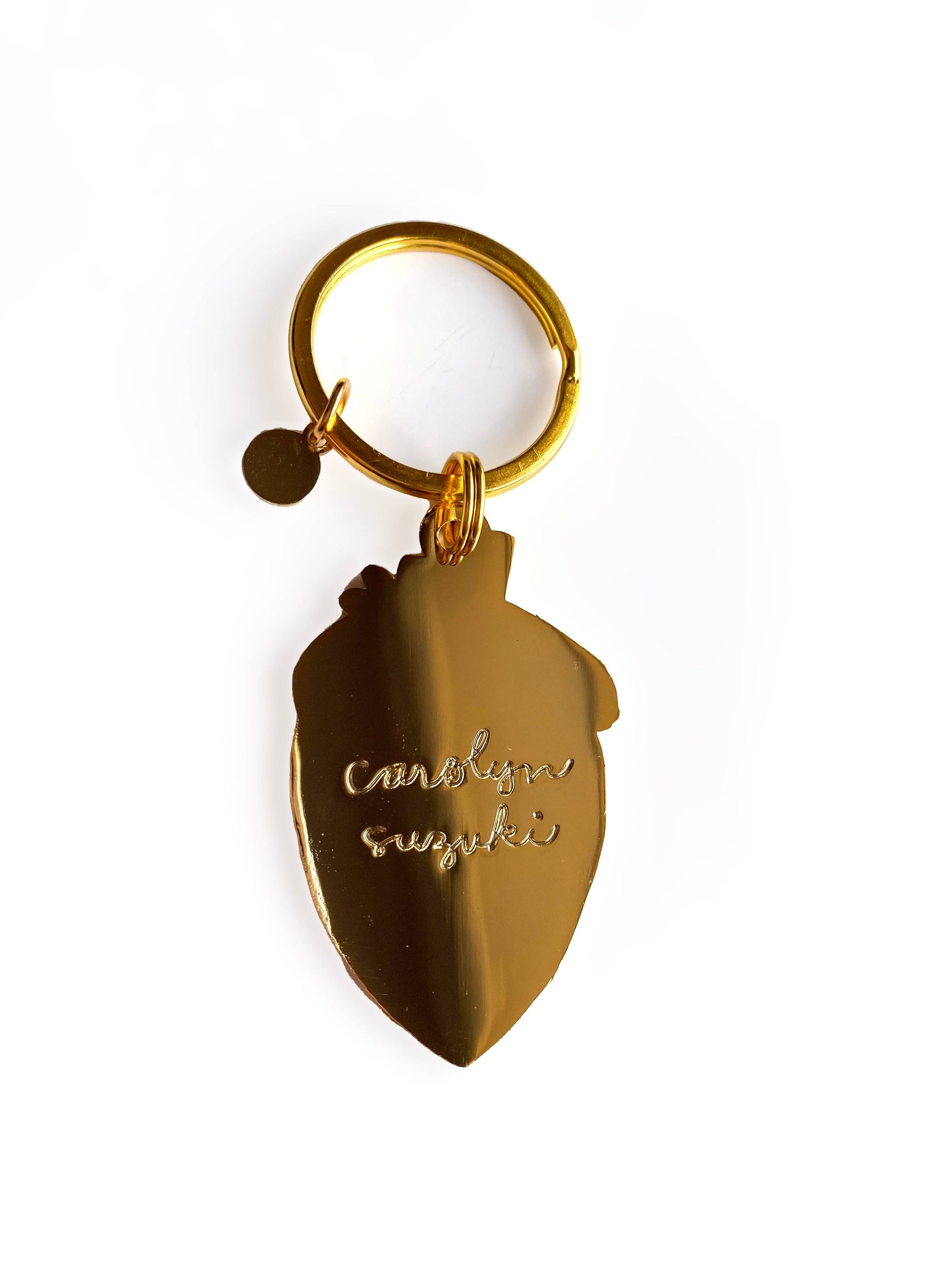 Backside of strawberry keychain. All gold with "Carolyn Suzuki" inscription. 