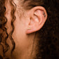 Single 14k gold plated stud earring -- reads "pasta" in handwritten script. Shown on ear for scale 