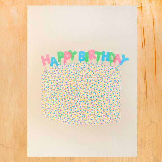 greeting card with a cake covered in round confetti sprinkles and candles on top that read "HAPPY BIRTHDAY" 