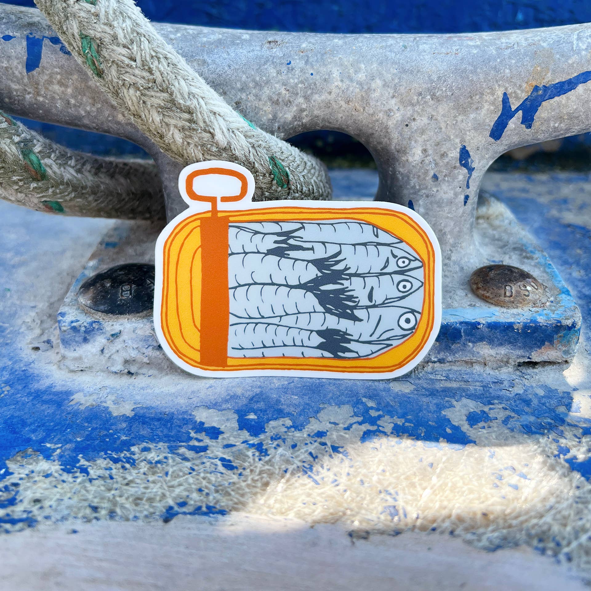 Matte sticker with illustration of an opened, mustard yellow, tinned fish can with packed sardines inside 