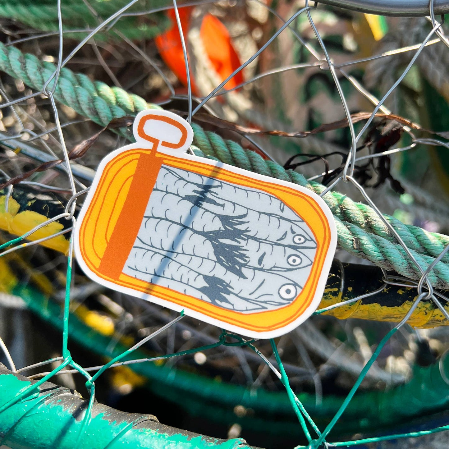 Matte sticker with illustration of an opened, mustard yellow, tinned fish can with packed sardines inside 