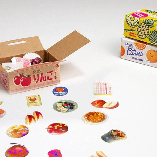 Cardboard box with colorful stickers of fruits and a box labeled 'Mister Citrus' on a white background.