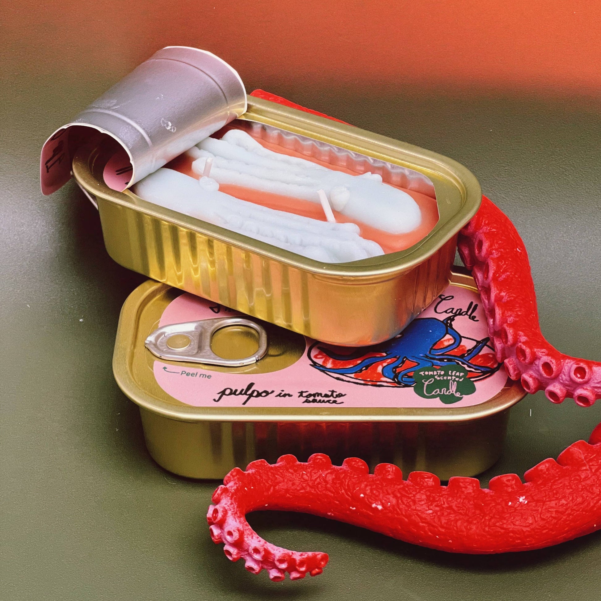 The Original Tinned Fish Candle- Pulpo in tomato sauce. Tinned seafood container has a picture of an octopus on it.  2 cans resting on top of eachother and the top one is open. 