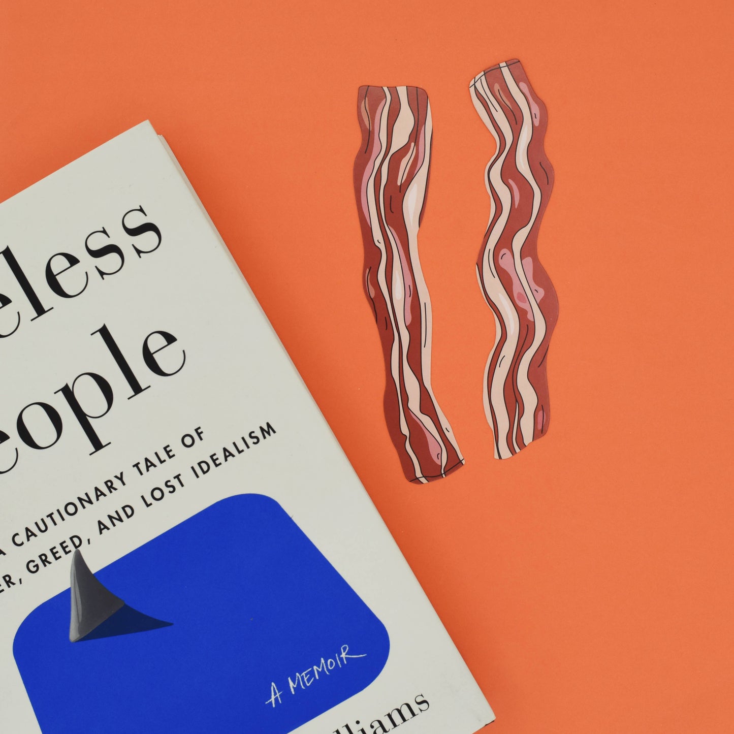 Book with two bacon-shaped bookmarks on an orange background