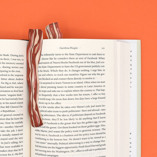 Two slices of bacon on an open book with an orange background