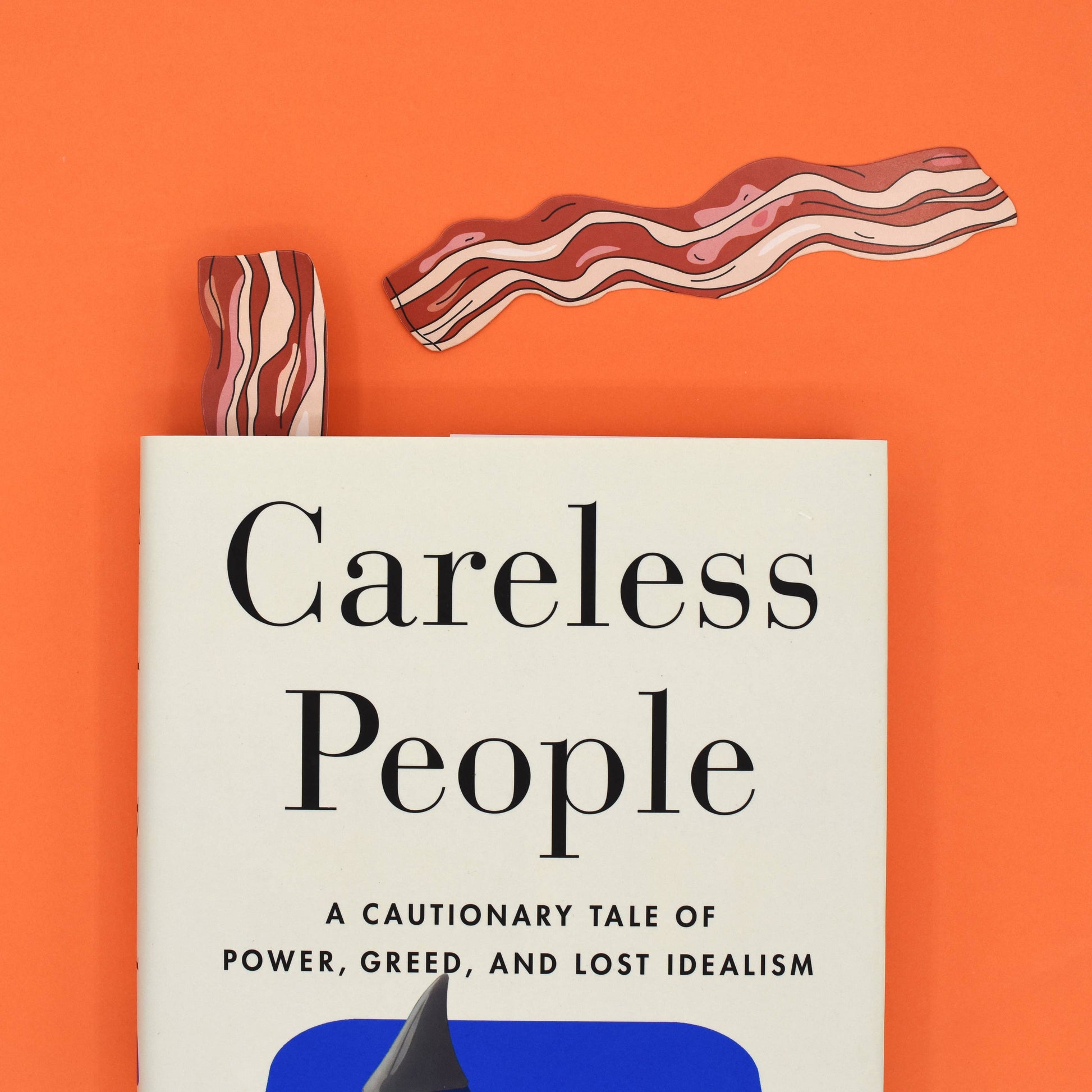 Book titled 'Careless People' on an orange background with bacon bookmarks