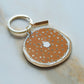 closer look at the bagel enamel keychain with seasoning detailing and a thin layer of schmear 