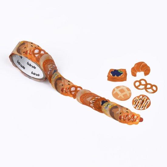 Roll of decorative washi stickers with bread design and small bakery-shaped items on a white background