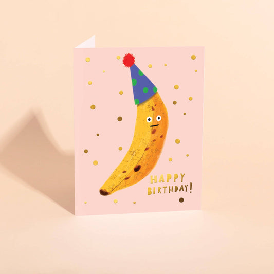 Birthday card with a banana wearing a party hat on a pink background