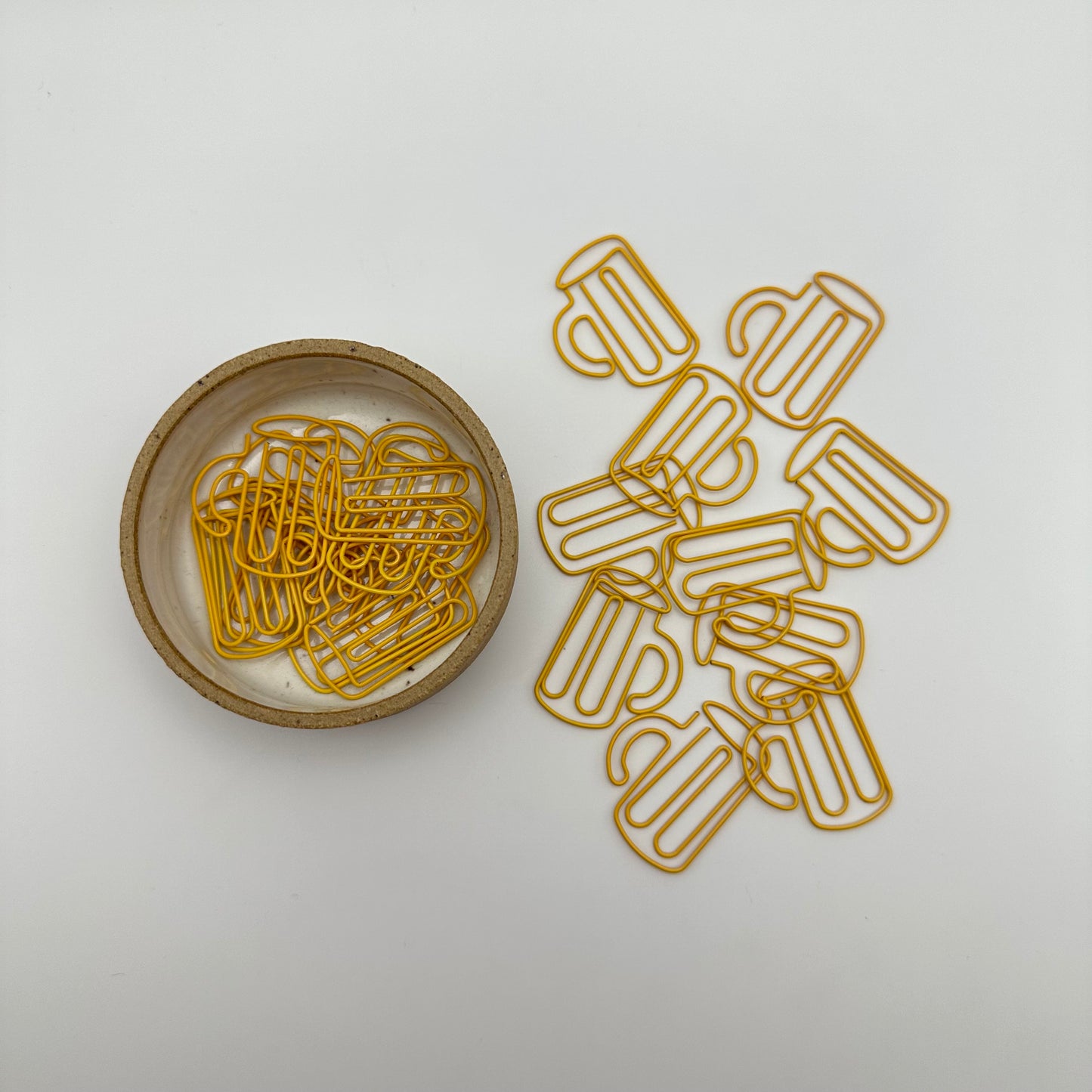 Pile of beer mug paperclips on table and in ramekin