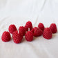 Red raspberry-shaped candles on a white fabric background
