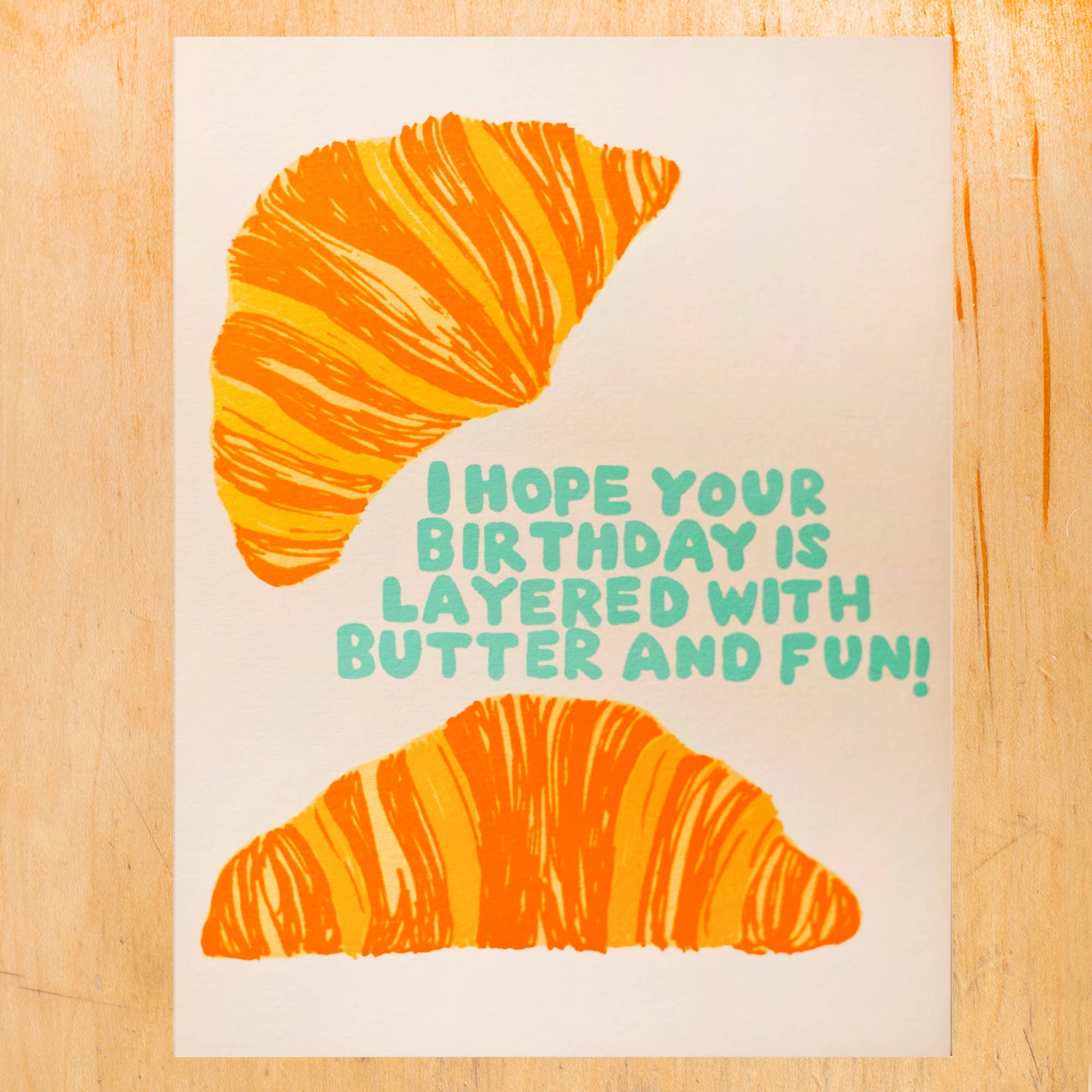 greeting card with illustrations of two croissants and text that reads "I hope your birthday is layered with butter and fun!" 