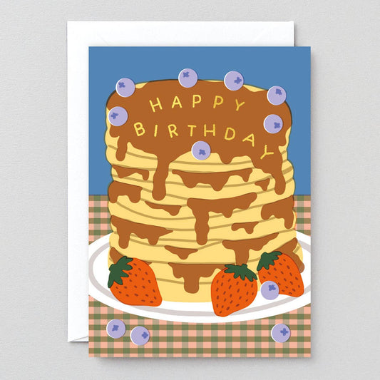 card with a stack of pancakes on it, decorated with blueberries and strawberries and text on top of the syrup that reads "Happy Birthday" 