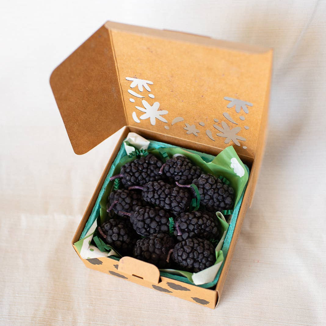 Box of black grapes on a white fabric background
