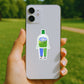 Phone case with a cartoon character sticker held by a hand outdoors