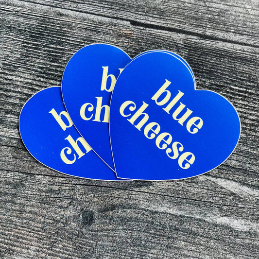 Three, blue, heart-shaped stickers with text in center that says "blue cheese"