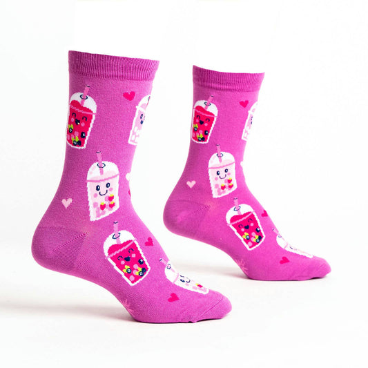Pink socks with colorful boba bubble tea drink illustrations and heart patterns on a white background