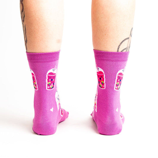 Pink socks with colorful boba bubble tea drink illustrations and heart patterns on a white background