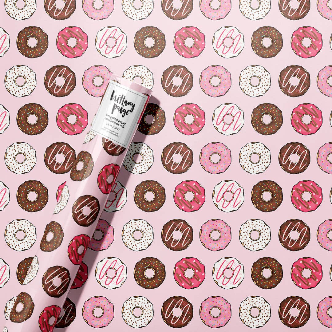 mostly pink wrapping paper with white, pink and brown donuts on it with various toppings