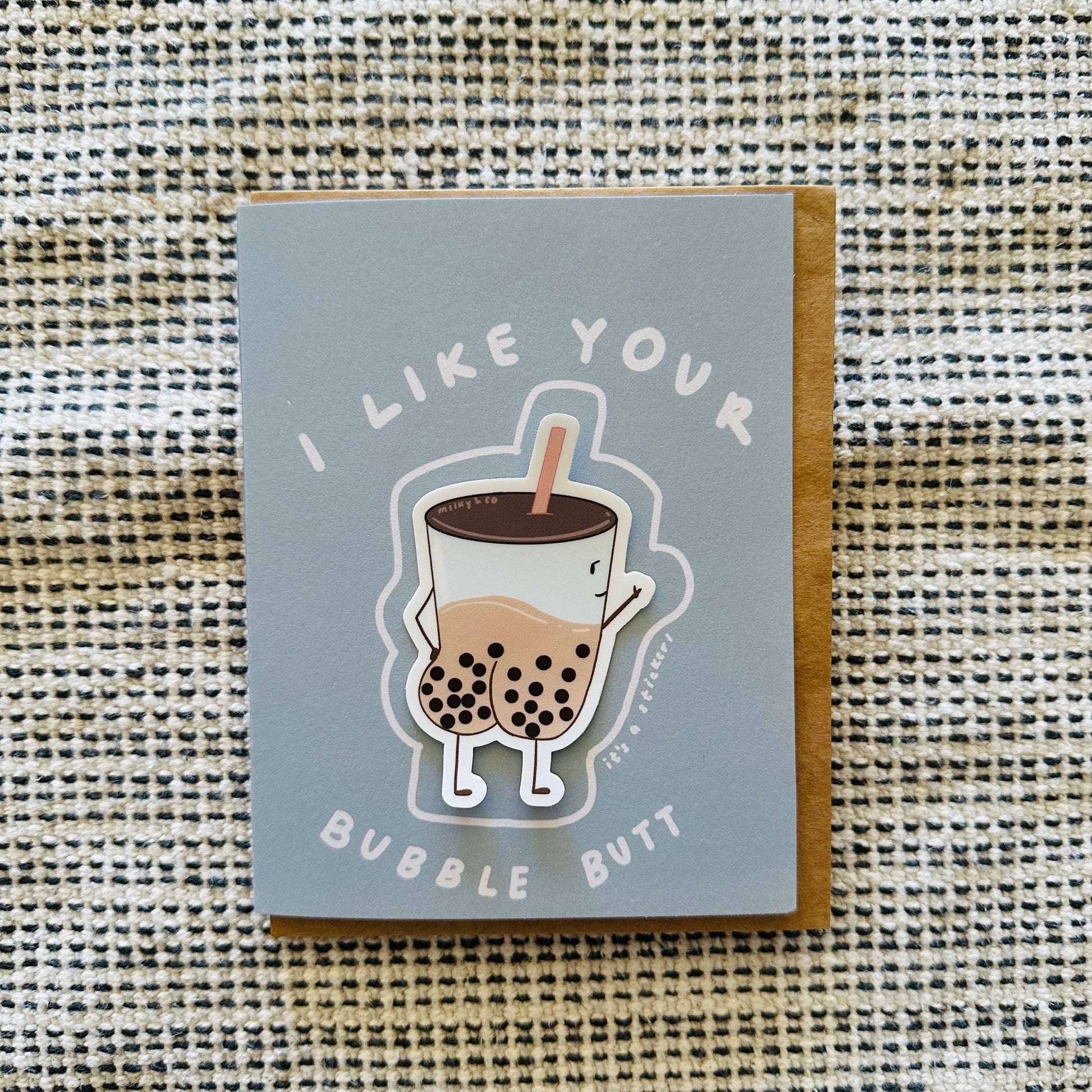 Greeting card that reads "I like your bubble butt" accompanied with a sticker of an illustrated boba cup with a butt filled with tapioca balls and milk tea