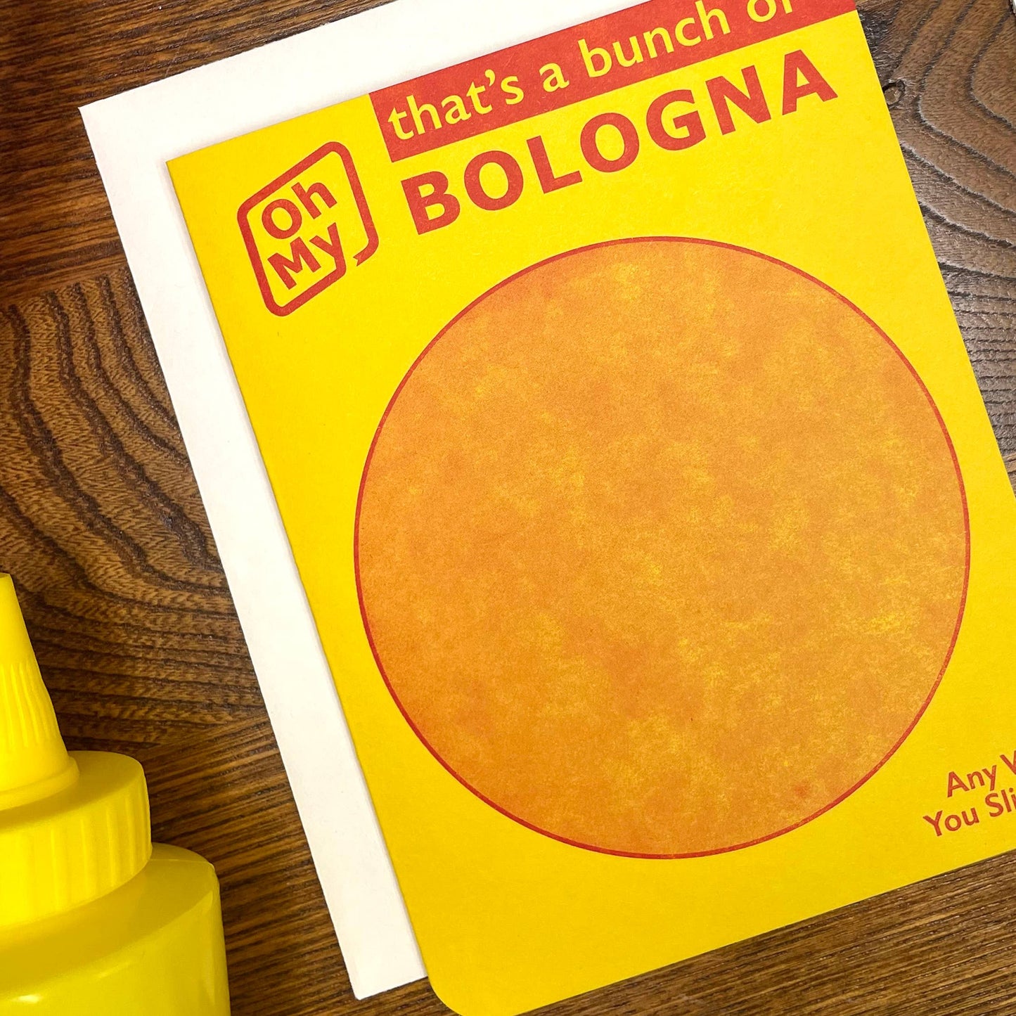 Greeting card with 'Oh my that's a bunch of bologna" text on a wooden surface with a mustard bottle