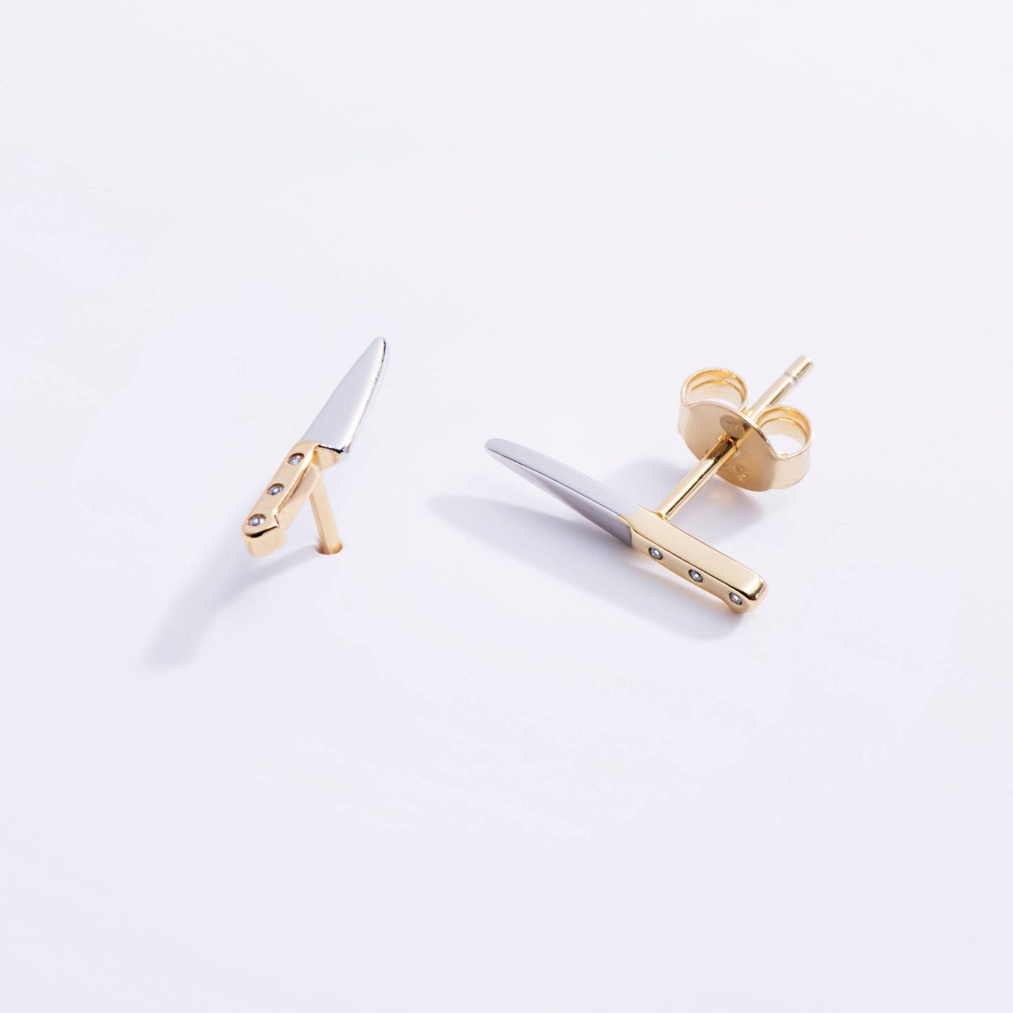 butcher knife shaped earrings with a gold handle and silver blade 
