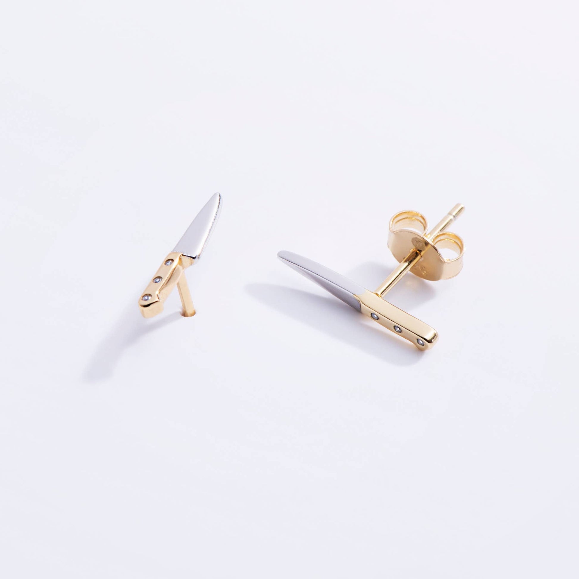 butcher knife shaped earrings with a gold handle and silver blade 