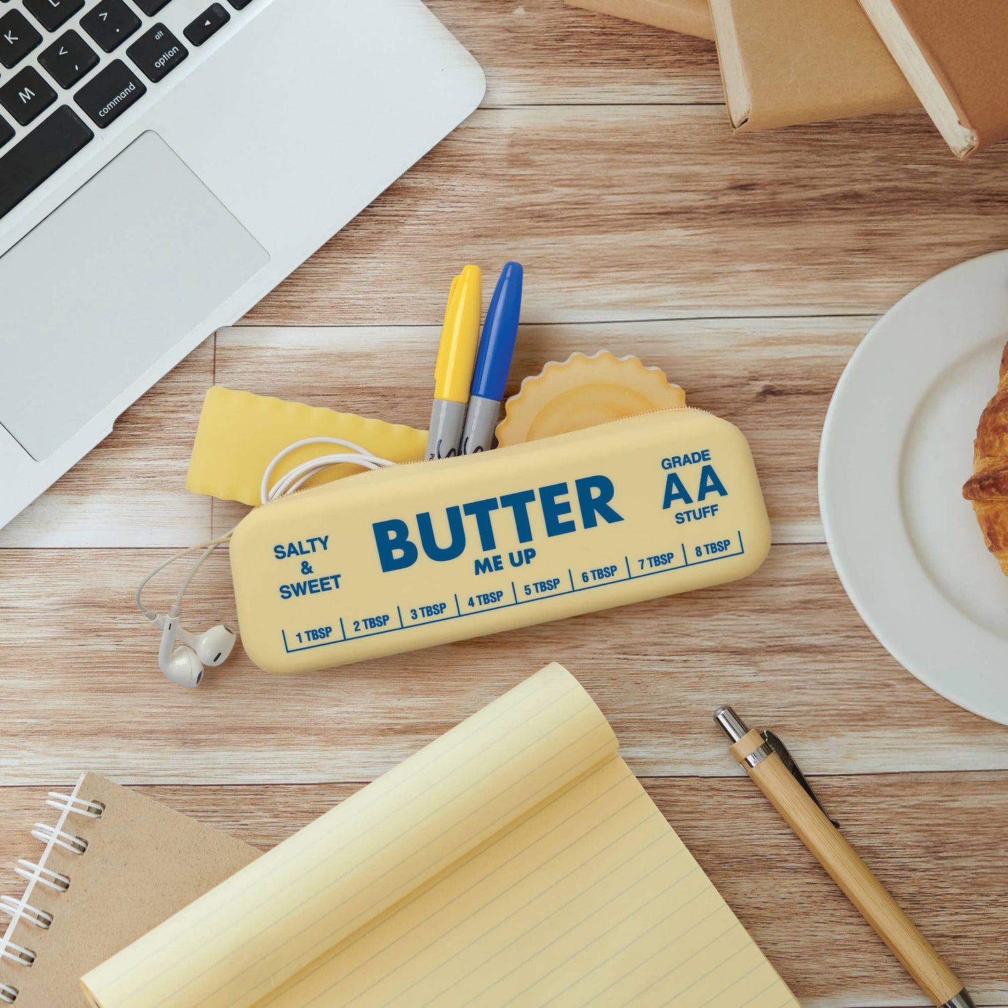 Butter shaped silicone pouch with office supplies on a wooden desk
