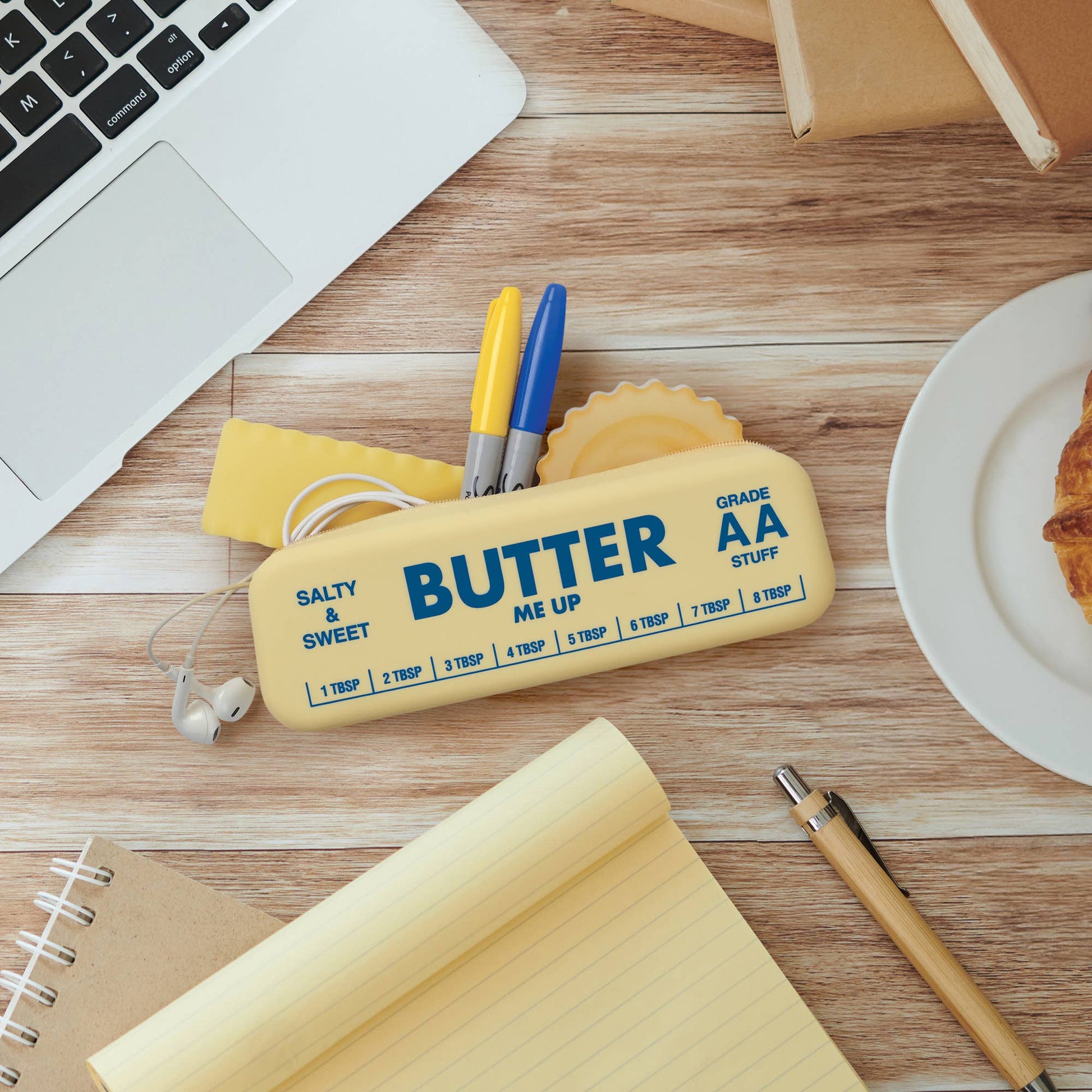 Butter shaped silicone pouch with office supplies on a wooden desk