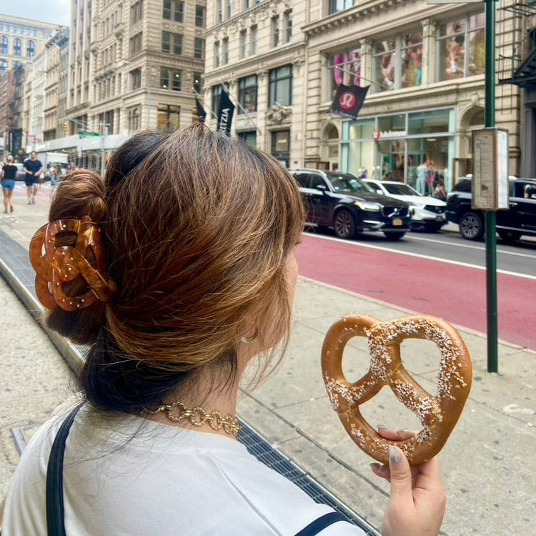 Pretzel hair clip in girl's hair while holding a real salted pretzel 