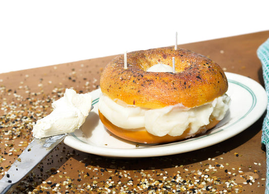 Everything bagel shown on a plate with a dinner knife full of real cream cheese.
