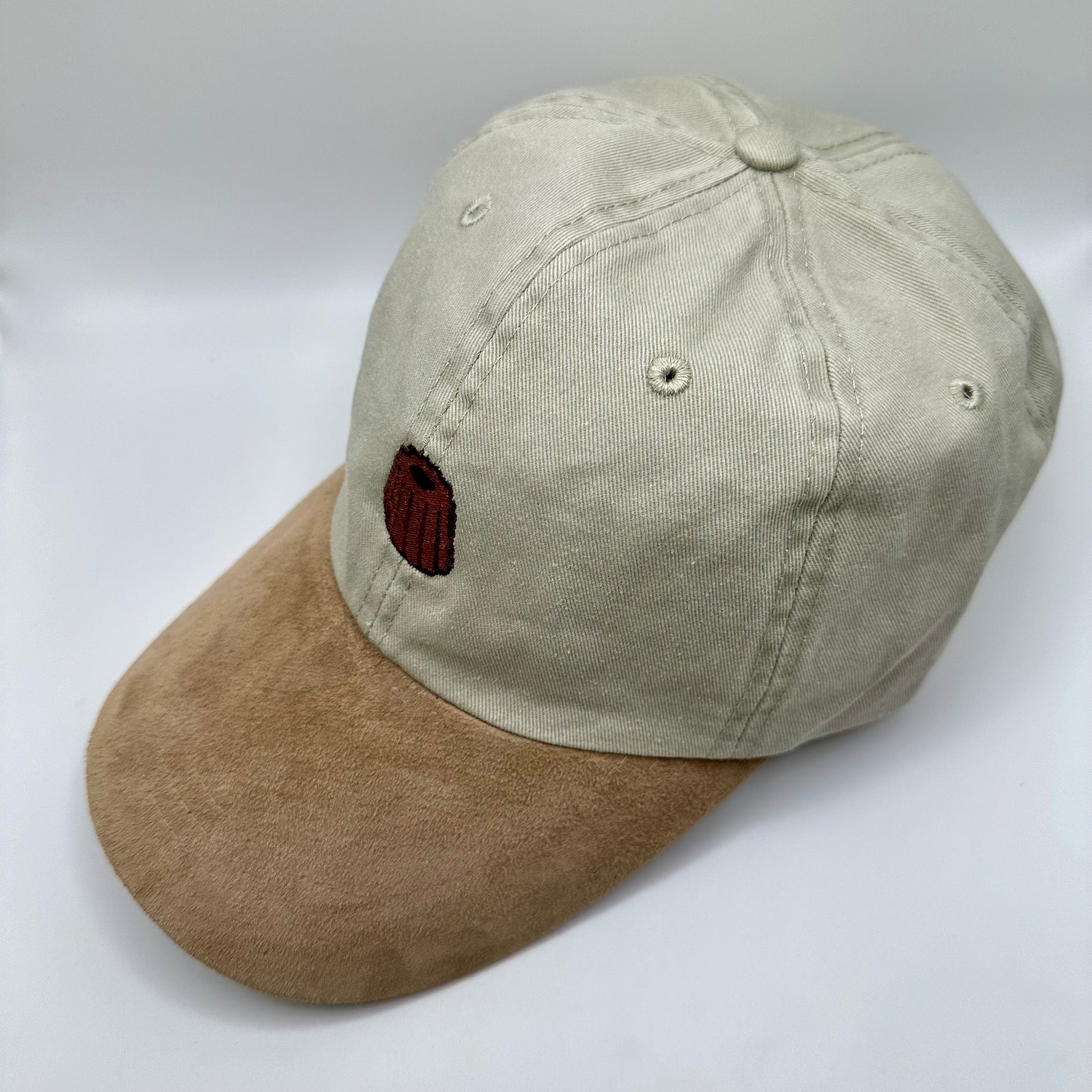 Beige Hat with suede-looking khaki bill. Canelê pastry embroidered on the top.