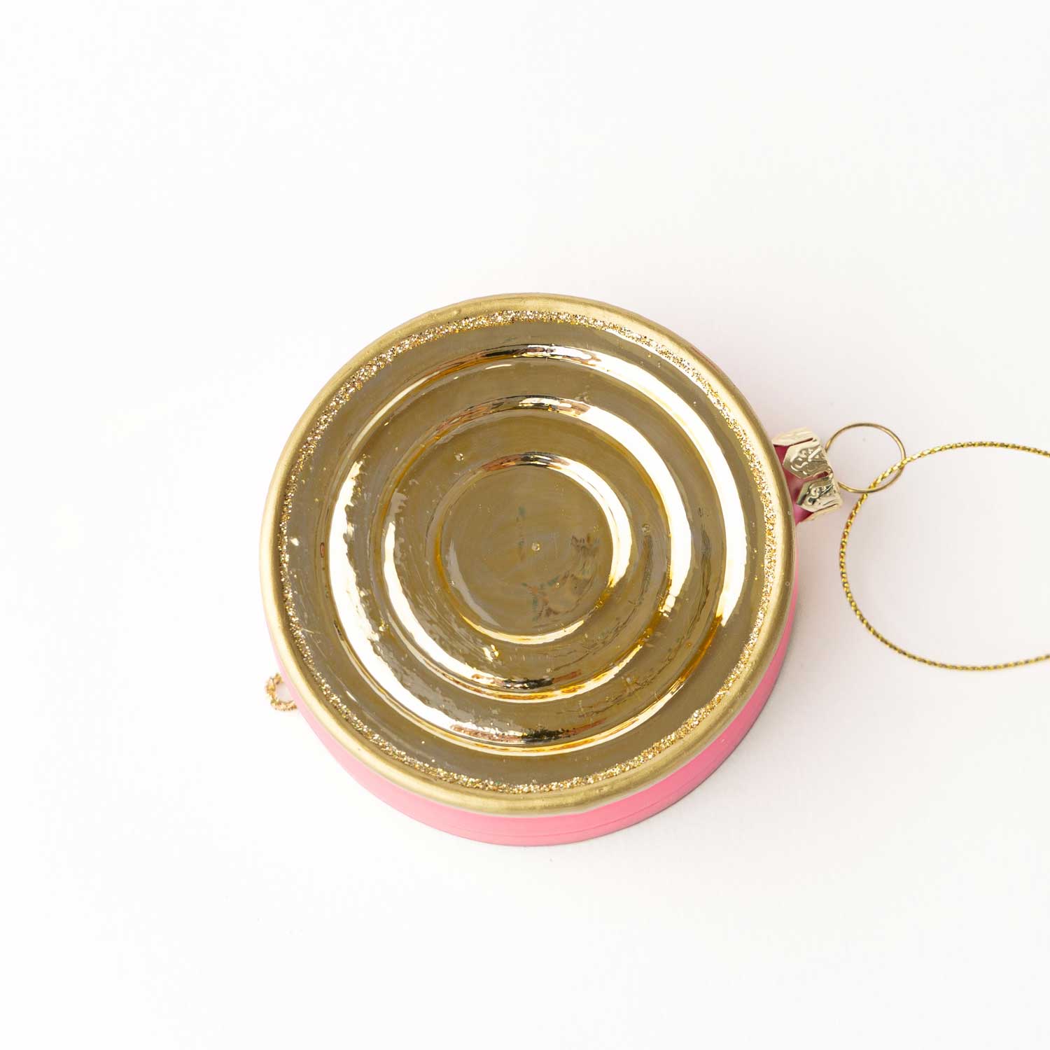 Gold and pink circular bottom of a caviar tin ornament on a white background