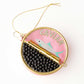 Decorative caviar tin ornament with fish design and 'CAVIAR' text on a pink background
