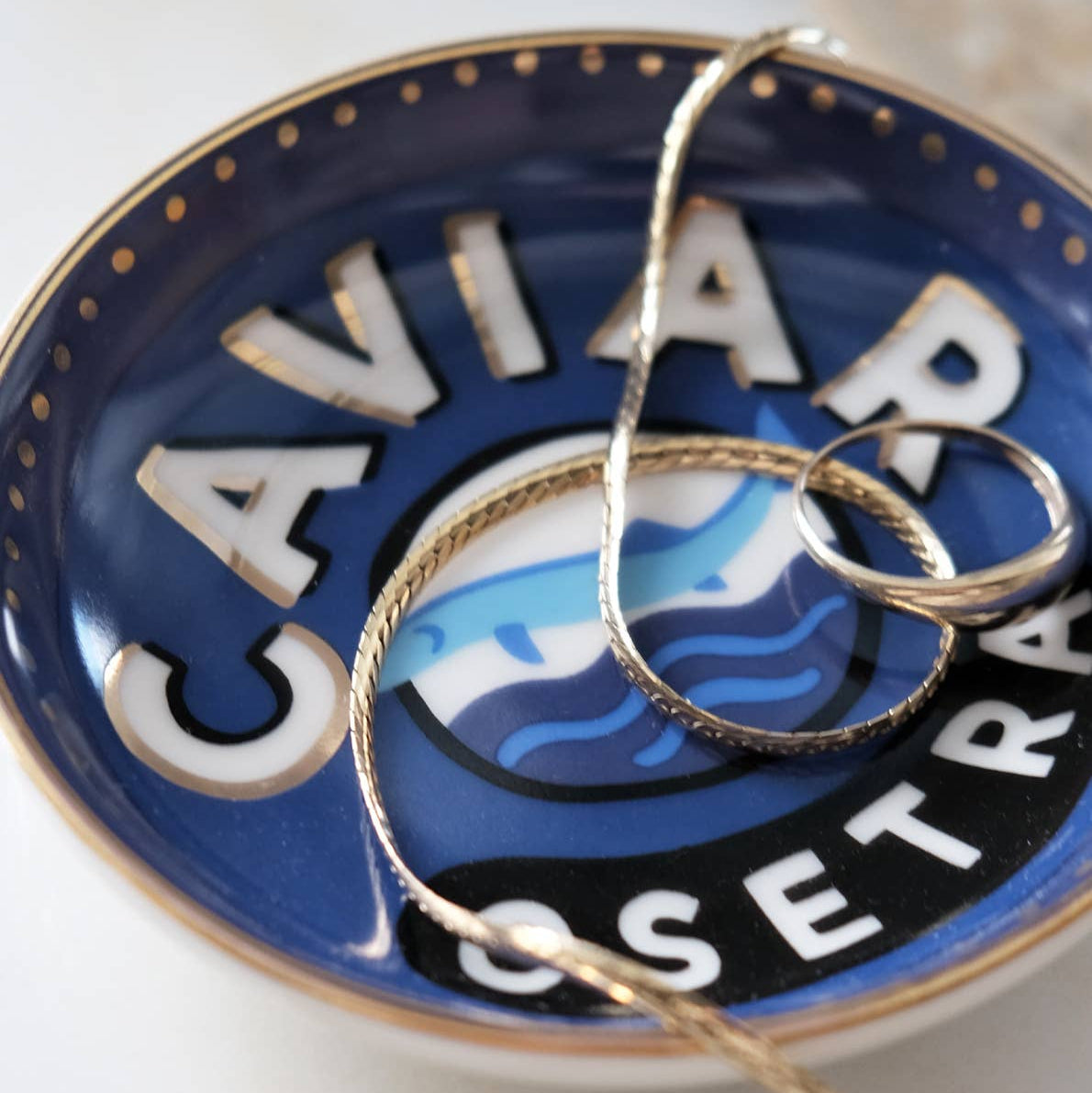 A ring and necklace on a blue, Caviar Osetra branded trinket dish.